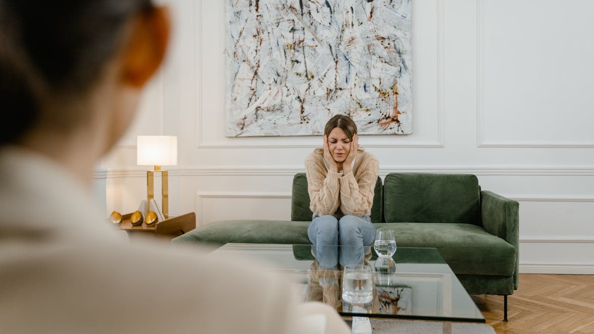 A woman in a counseling session, looking distressed and contemplative, indoors.